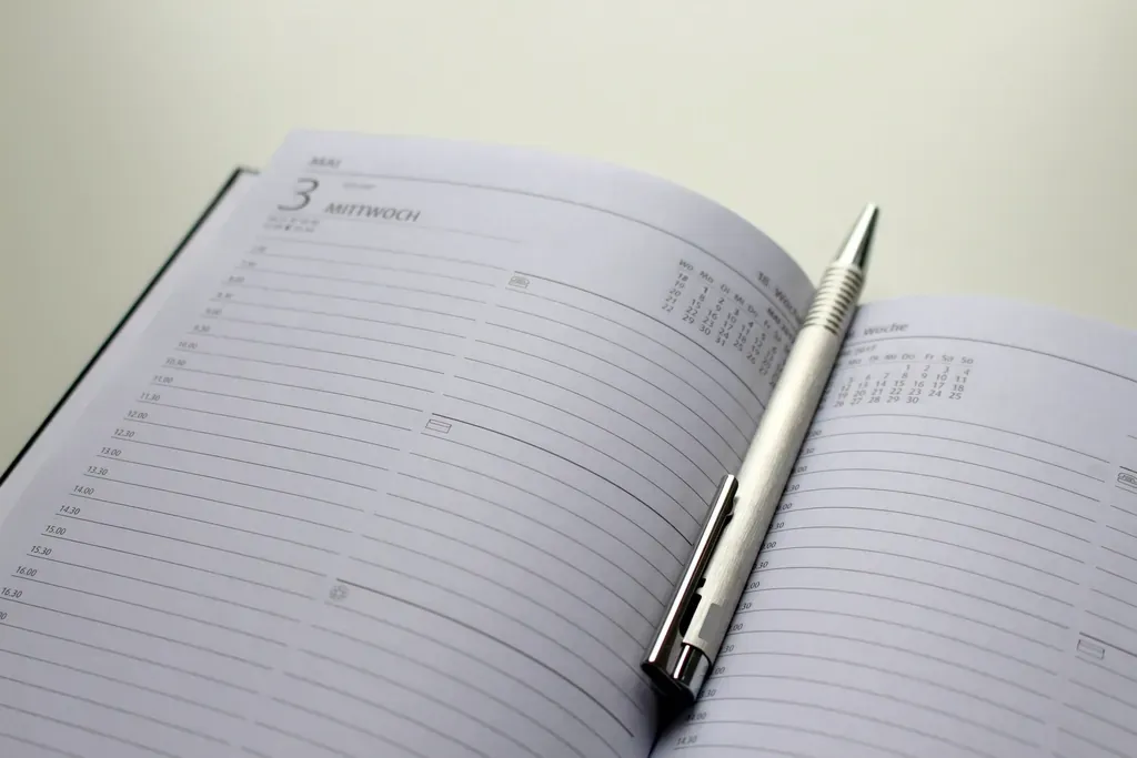 An open day planner with lined hourly pages and a silver pen resting across it.